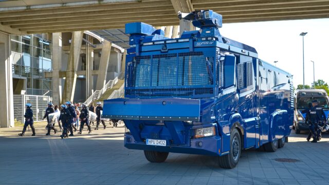 🚔 TAJFUN IV. Policyjny kolos do zadań specjalnych

To jeden z najbardziej charakterystycznych pojazdów polskiej Policji. Tajfun IV to specjalistyczny pojazd przeznaczony m.in. do zabezpieczania zgromadzeń, imprez masowych oraz działań w sytuacjach wymagających użycia armatki wodnej.

🚒 Najważniejsze dane:
🔹 podwozie: Scania P450 B6x6HZ
🔹 napęd: 6×6
🔹 silnik: 450 KM
🔹 DMC: do 35 ton
🔹 zbiornik wody: 9000 litrów
🔹 zbiornik środka barwiącego: 100 litrów
🔹 zbiornik gazu drażniącego: 100 litrów
🔹 wydajność pompy: do 5000 l/min przy 15 bar
🔹 zasięg działek: około 50 metrów
🔹 załoga: 3 funkcjonariuszy

💦 Tajfun IV wyposażony jest w dwa działka wodne umieszczone na dachu kabiny. Każde z nich może podawać strumień zwarty lub rozproszony, a operatorzy sterują nimi z wnętrza zabezpieczonej kabiny.

🛡️ Załogę chronią m.in. kuloodporne szyby klasy BR2, wzmocnione elementy nadwozia oraz system filtrowentylacji. Pojazd posiada również wkładki umożliwiające jazdę po przebiciu opon.

🔥 Tajfun IV wyposażono także w system zraszania pojazdu wodą lub pianą, chroniący go przed podpaleniem.

🚧 Z przodu znajduje się hydrauliczny lemiesz, który może służyć do usuwania przeszkód i barykad o masie do około 500 kg.

📹 Nad bezpieczeństwem i obserwacją otoczenia czuwa rozbudowany system kamer. Pojazd posiada 8 kamer na zabudowie oraz 2 kamery zamontowane na działkach.

🇵🇱 Pierwsze Tajfuny IV trafiły w 2021 roku do Oddziałów Prewencji Policji w Warszawie, Gdańsku, Katowicach, Poznaniu i Krakowie. Pojazdy były również wykorzystywane podczas działań na granicy polsko-białoruskiej.

💬 Tajfun IV to 35-tonowy, sześciokołowy specjalista, który łączy funkcję armatki wodnej, pojazdu ochronnego i maszyny do usuwania przeszkód.